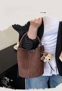 Detailansicht der braunen Wildleder-Beuteltasche mit Kontrastnähten und Teddybär-Anhänger