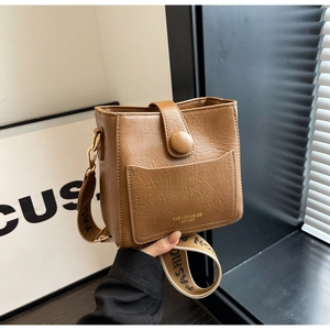 Vue détaillée du sac seau en cuir marron avec une large bandoulière à motif fashion