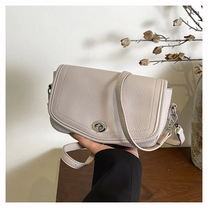 Detalle del bolso bandolera de cuero gris con cierre giratorio plateado y correa ajustable