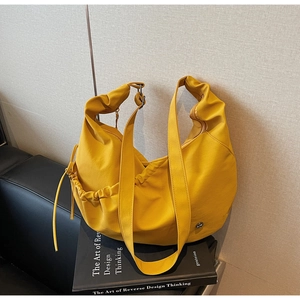 Close-up of ginger yellow hobo bag with drawstring sides and wide shoulder strap