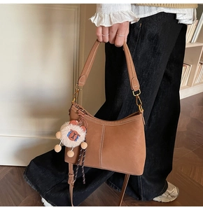 Détail d'un sac cabas en cuir marron avec surpiqûres blanches et charme agneau peluche