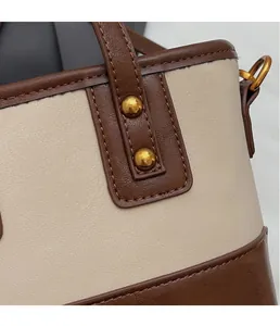 Détail du sac seau en cuir grainé avec rivets dorés et surpiqûres contrastées