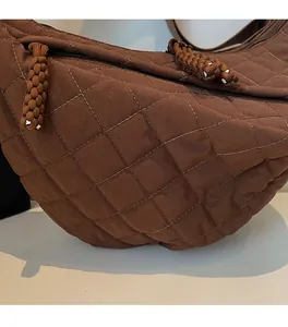 Gros plan du sac en toile matelassée marron avec coutures en losange et zip tressé