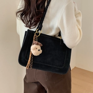 Detail of suede tote bag featuring woven texture edges and a cute plush bear charm