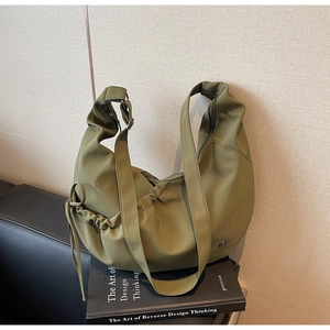Detail view of the side drawstring design and metal logo on the green dumpling bag
