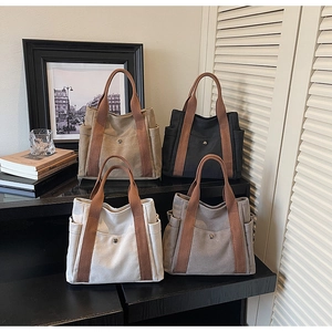 Detailed view of canvas tote bags in four neutral colors with contrasting brown handles
