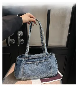 Close-up of washed blue denim handbag with silver metal buckle and reinforced stitching