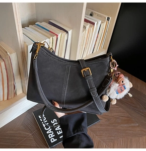 Vue détaillée du sac gris mat avec surpiqûres blanches et charme en peluche