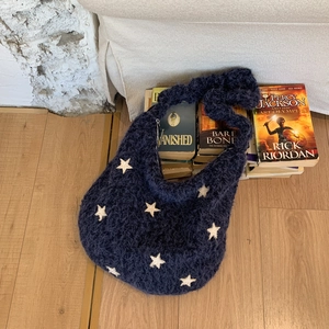 Detail of navy blue knit hobo bag with white star pattern on vintage books