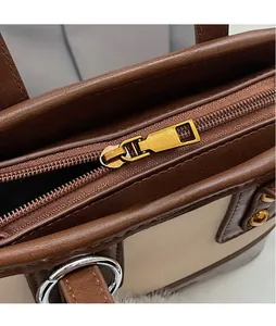 Détails de la fermeture éclair dorée et coutures du sac à main seau en cuir marron