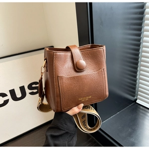 Détail d'un sac seau rétro marron montrant le grain de litchi et la bandoulière tissée