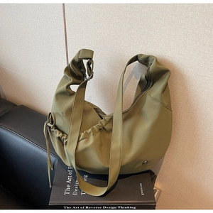 Detail shot of a green hobo bag featuring side drawstring design and a metal logo