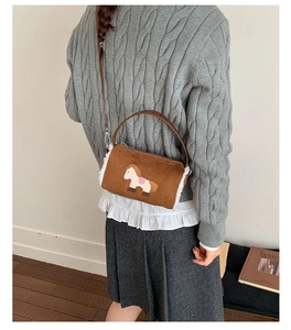 Detail of brown suede crossbody bag with white faux shearling trim and horse embroidery