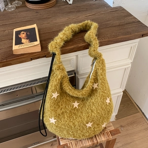 Detail view of mustard yellow plush shoulder bag with white star patches and drawstring