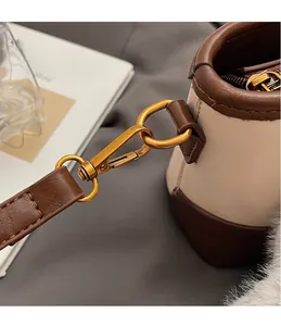 Détail du crochet doré vintage et des finitions en cuir marron sur un sac seau beige