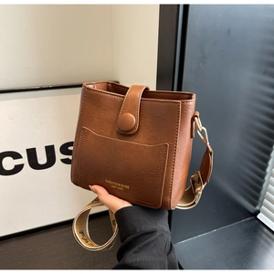 Détail du sac seau en cuir marron avec sangle jacquard et poche avant pratique