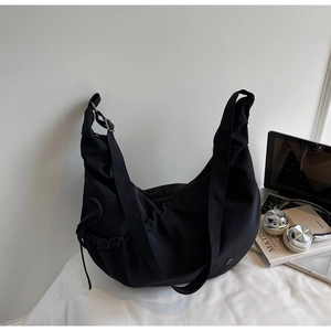 Detail of minimalist black hobo bag with adjustable strap and drawstring side pocket