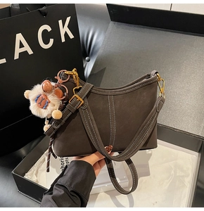 Vue détaillée du sac bandoulière marron foncé avec coutures blanches dans sa boîte cadeau