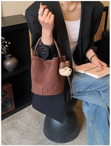 Detail einer braunen Wildleder-Beuteltasche mit Ziernaht und Plüschtier-Anhänger
