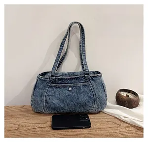 Detail view of retro washed denim tote bag with front pocket and metal buttons on wood desk