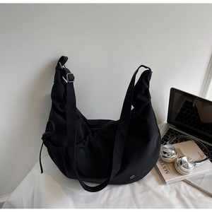 Minimalist black crescent crossbody bag with adjustable wide strap and nylon texture