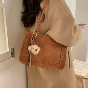 Detail of vintage brown suede tote bag with woven shoulder strap and cute bear charm