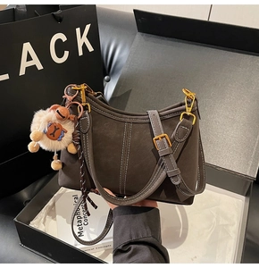 Détail du sac en cuir mat marron foncé avec surpiqûres blanches et charme mouton