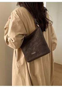 Detail einer braunen Vintage-Schultertasche mit elegantem Riemen und Metall-Logo