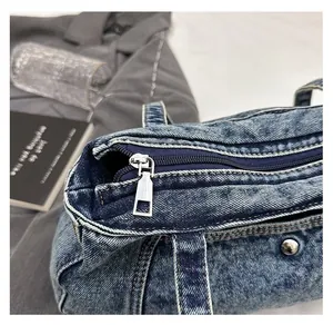 Close-up of smooth metal zipper and white stitching on light blue washed denim bag