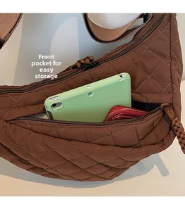 Gros plan d'un sac bandoulière matelassé marron avec poche zippée avant pratique