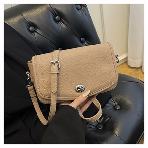 Detalle de bolso bandolera beige de cuero granulado con cierre giratorio plateado