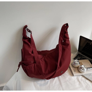 Macro detail of wine red crescent nylon bag featuring adjustable drawstring side folds