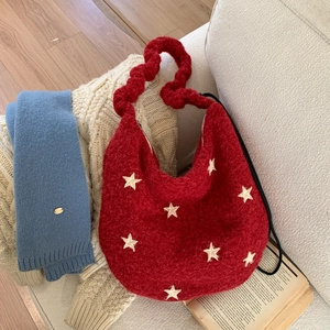Detail of red knit shoulder bag featuring white star embroidery and thick braided handle