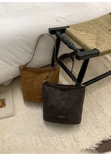 Detail von hellbraunen und dunkelbraunen Wildleder-Schultertaschen mit Logo auf Stühlen