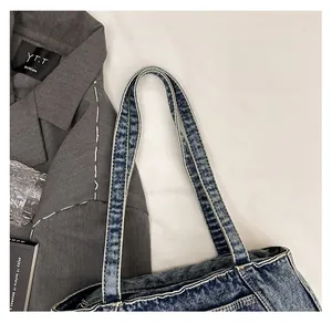 Close-up of durable double-stitched handle on a vintage blue washed denim shoulder bag