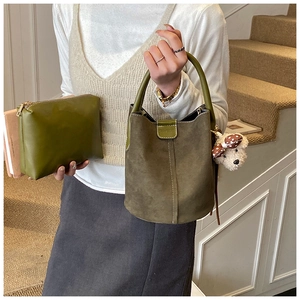Detail der olivgrünen Eimer-Tasche aus Wildleder mit Clutch und Plüsch-Anhänger