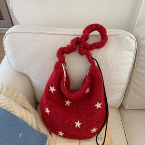 Macro shot of red plush shoulder bag with white star pattern and braided handle