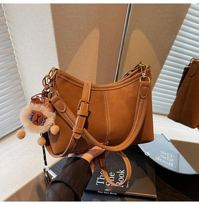Détail du sac à main en cuir marron avec coutures contrastées et porte-clé en peluche