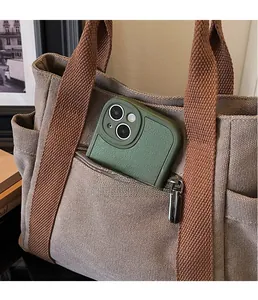 Detail of canvas tote bag featuring a front zipper pocket with a green mobile phone