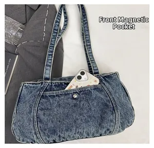 Detail of blue washed denim crossbody bag featuring a front pocket for smartphone storage