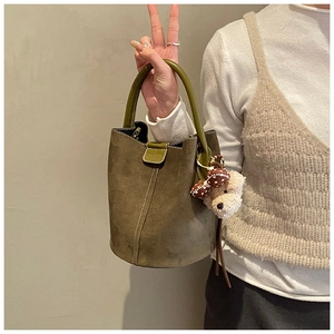 Detail einer dunkelgrünen Wildleder-Beuteltasche mit Kontrastnaht und Plüschbär-Anhänger