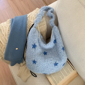 Detail of light blue fuzzy hobo bag with dark blue star embroidery on a cozy sofa