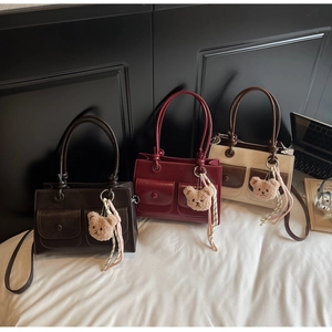 Detailed view of square faux leather handbags with front pockets and teddy bear charms