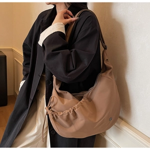 Detail of khaki hobo bag with drawstring pleats and adjustable strap on a model