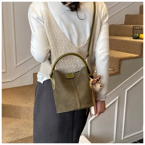 Details der olivgrünen Eimer-Tasche aus Wildleder mit Rundgriff und kleinem Hundeanhänger