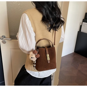 Détail du sac seau en daim marron foncé avec pendentif ours et fermoir doré chic