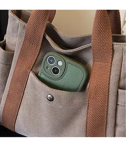 Close-up of front pocket on canvas tote bag with metal snap and a green smartphone