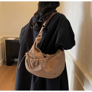 Close-up of khaki drawstring dumpling bag with soft nylon texture and pleated details