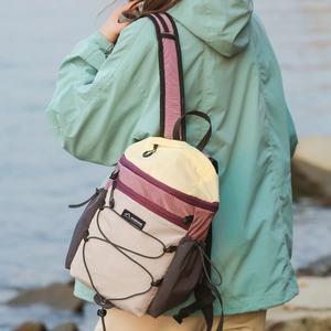 Outdoor model shot of lightweight color-block foldable backpack with bungee cord detail