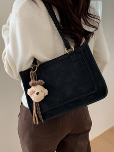 Retro black shoulder tote bag with braided edges and cute yellow plush charm on strap